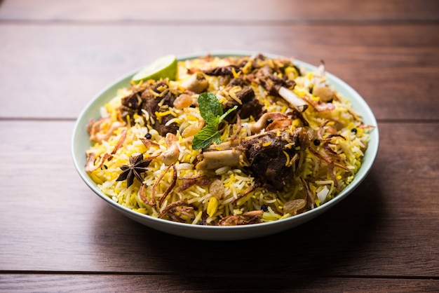 Hammel- oder Lammbiriyani mit Basmatireis, serviert in einer Schüssel auf stimmungsvollem Hintergrund