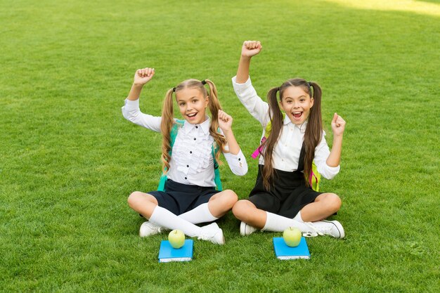 Han comenzado las vacaciones. Los niños felices celebran las fiestas al aire libre. Las niñas se sientan en la hierba verde. Vacaciones escolares. Vacaciones de verano y vacaciones. Ocio y tiempo libre. Se acabo la escuela.