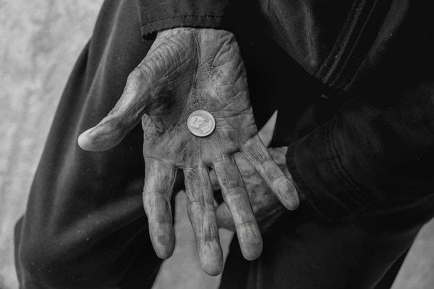 Hand alter Mann bettelt um Geld wegen des Hungers auf dem Holztisch Vintage Ton