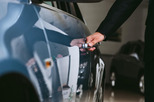 Hand auf den Autogriff, glücklicher Mann, der ein Auto in einem Autohaus oder Showroom berührt