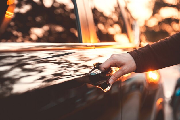 Hand auf Griff. Nahaufnahme der Frauenhand, die eine Autotür mit Sonnenlichteffekt öffnet.