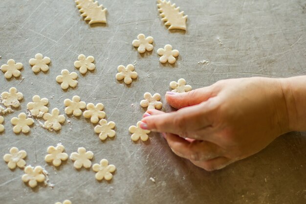 Hand berührt Blume aus Teig. Kleine Stücke von rohem Gebäck. Baker macht Dekoration für Lebensmittel. Rezept und Kunstwerk.