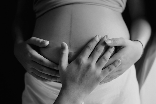 Hand berührt den Bauch einer schwangeren Frau