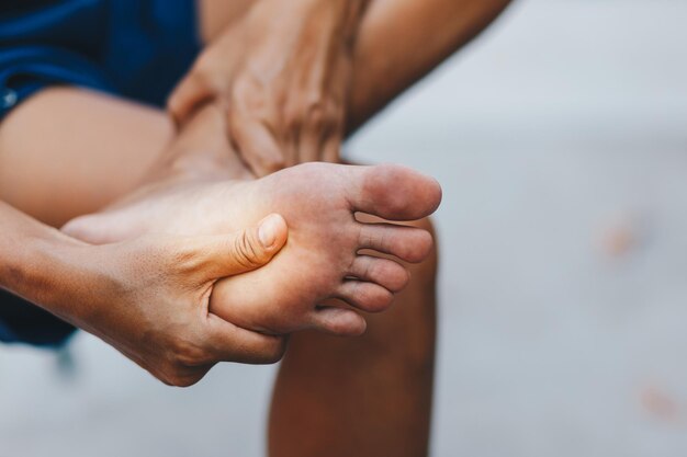 Hand berührt Füße im Schmerz