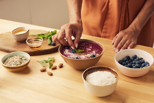 Hand der jungen frau, die minzblatt auf smoothie legt