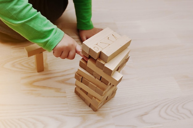 Hand des Babys, das ein Entwicklungsspiel aus Holzblöcken spielte