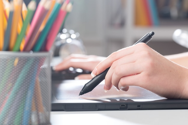 Hand des Designers mit einem Stift auf einem Tablet