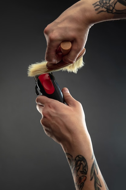 Hand des Friseurs mit Ausrüstung auf schwarzem Tisch.