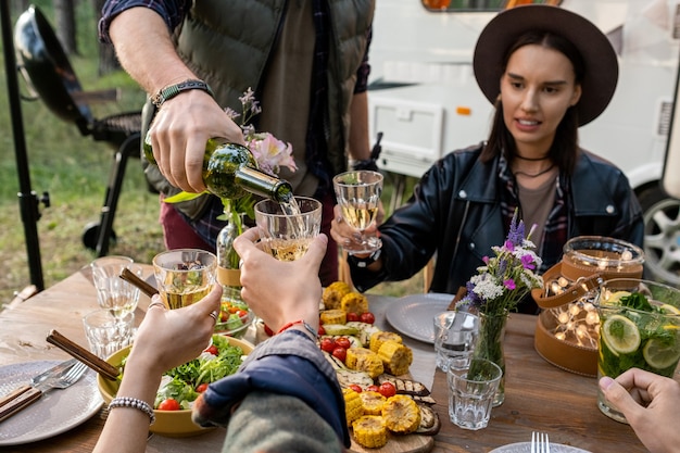 Hand des jungen Mannes, der Wein in Glas Freund gießt