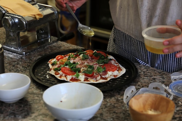 Hand des Küchenchefs, der Pizza in der hausgemachten Küche macht