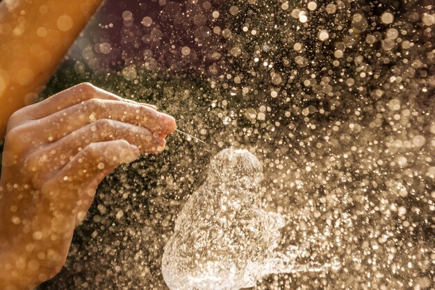 Hand des Mädchens mit Wasserspritzen auf schwarzem Hintergrund