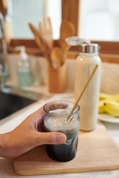 Foto hand des mannes, der ein glas proteinshake mit wiederverwendbarem bambusstroh hält