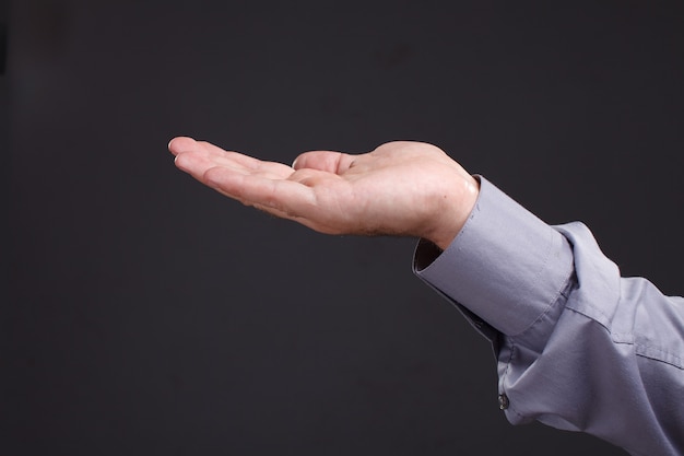 Hand des Mannes, der etwas lokalisiert auf einem dunklen Hintergrund hält