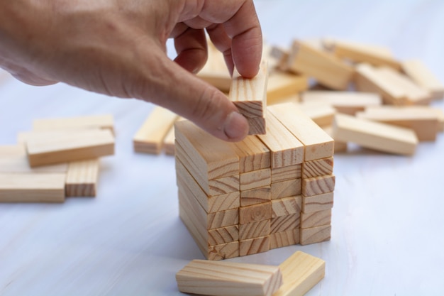 Hand des Mannes, die eine Spitze von Holzklötzen über Holzklotz hält