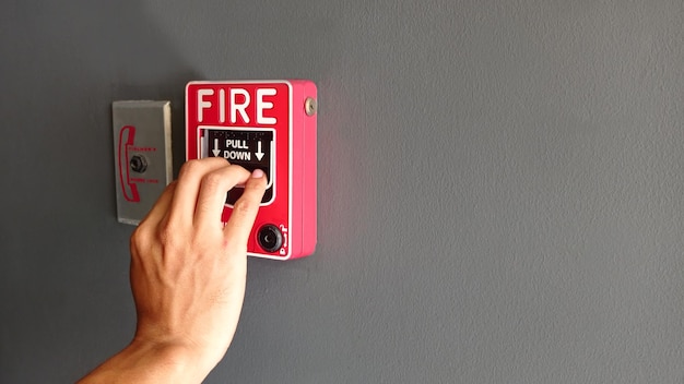 Hand des Mannes Feuermelder auf die weiße Wand als Hintergrund für Notfall ziehend