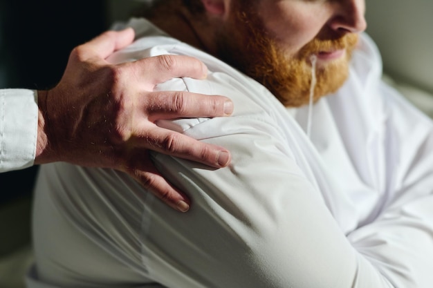 Foto hand des psychiaters einer psychiatrischen klinik auf der schulter eines patienten in zwangsjacke