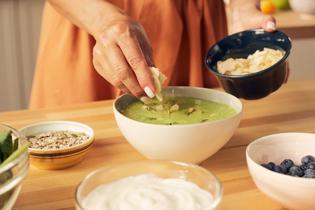 Hand des weiblichen Dekorations-Smoothies mit Mandelflocken