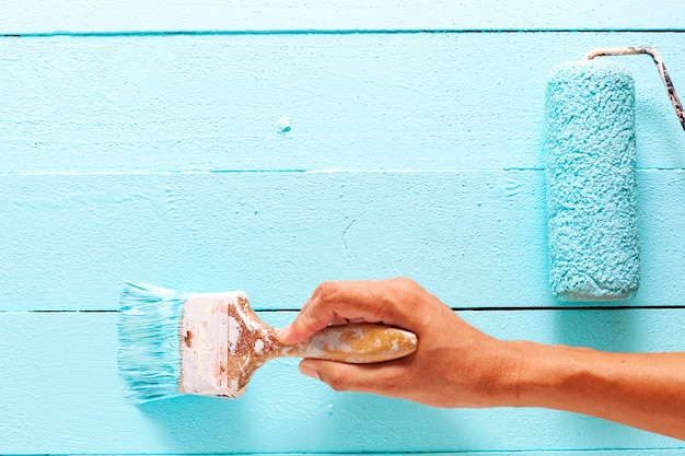 Hand, die blaue Farbe auf weißer hölzerner Planke malt