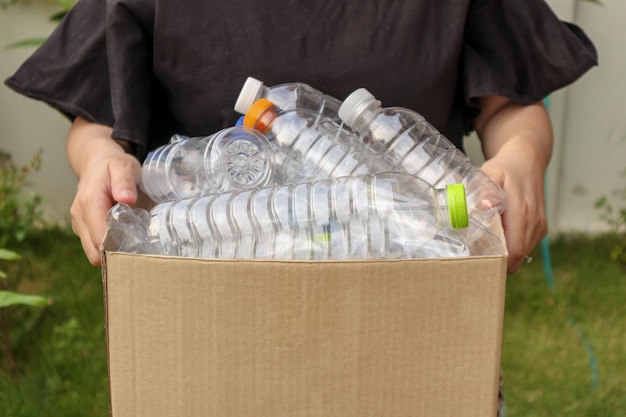 Hand, die braune Recycling-Müllbox mit Plastikflaschen hält