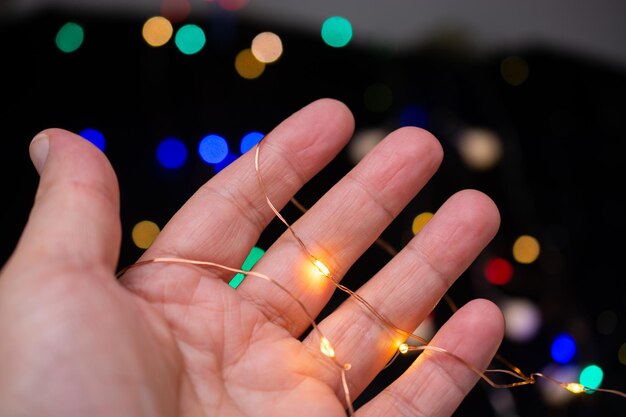 Hand, die bunt leuchtende Lichterkette hält Urlaub festliche Weihnachtsdekoration Weihnachtsbeleuchtung