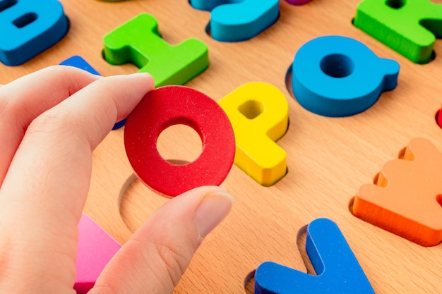 Hand, die bunte Buchstaben O aus Holz hält