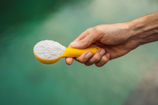 Hand, die Chlor für Wasser im Pool hält