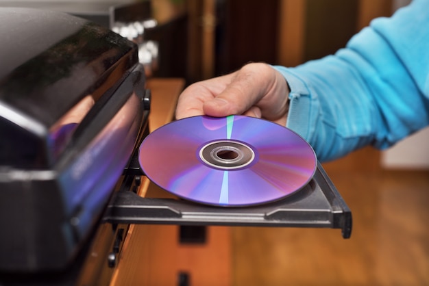 Hand, die DVD hält, die zum Videoplayer einfügt