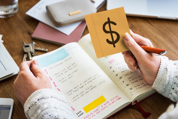 Hand, die ein Dollarzeichen auf einer klebrigen Anmerkung hält