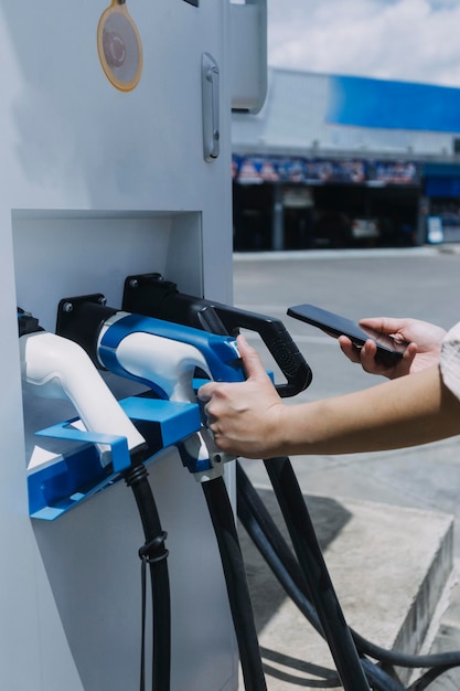 Hand, die ein Ladegerät in eine Steckdose für Elektroautos einstecktElektroauto oder EV wird an der Station aufgeladen