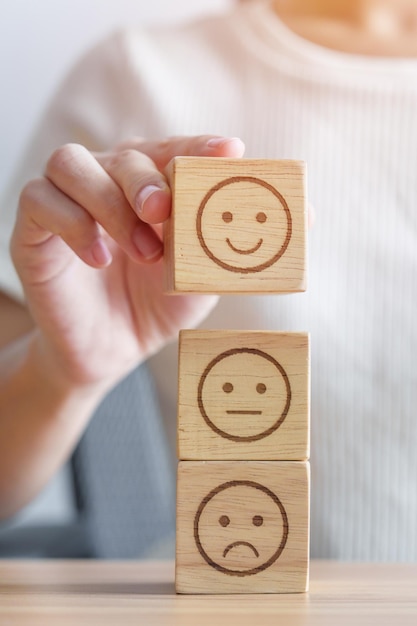 Hand, die ein Lächelngesicht aus dem Emotionsblock für die Kundenbewertung auswählt