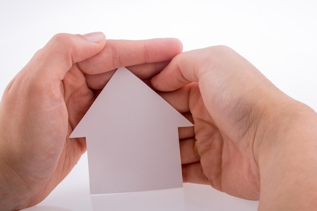 Hand, die ein Papierhaus hält