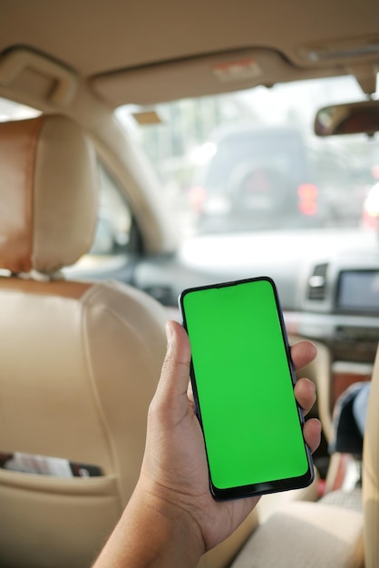 Hand, die ein Smartphone mit leerem Bildschirm in einem Auto hält