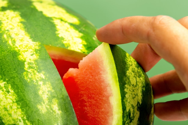 Hand, die ein Stück frische Wassermelone nimmt