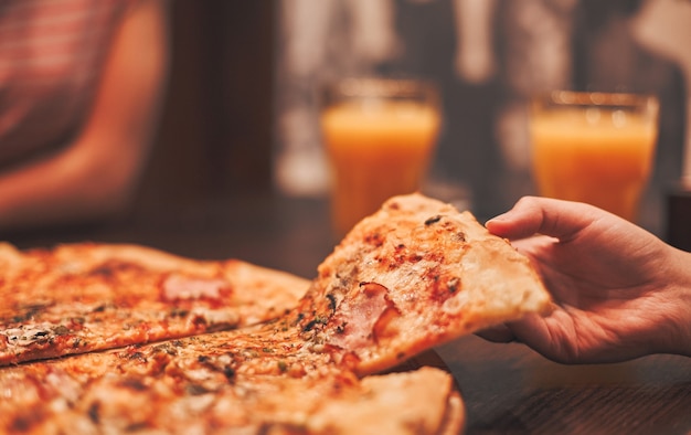 Hand, die ein Stück Pizza nimmt, Nahaufnahme