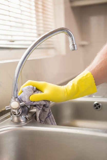 Hand, die ein Waschbecken mit Stoff säubert