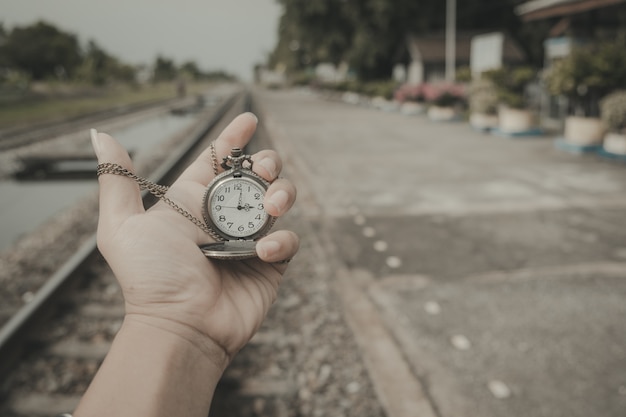 Hand, die eine Uhr auf den Bahnen hält, reflektiert eine Reise, die nie Vintage-Stil beendet.