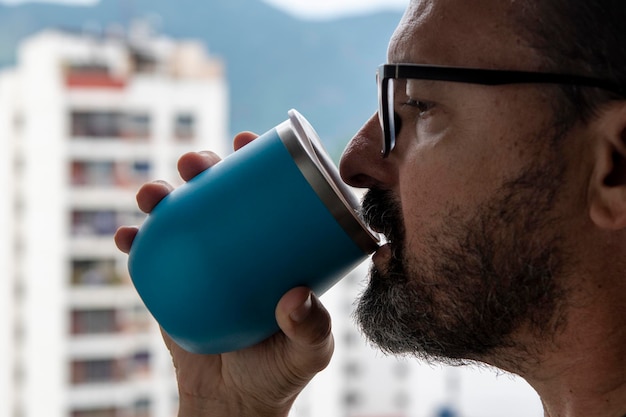 Hand, die einen Becher Wasser mit Blick auf den Hintergrund der Stadt hält