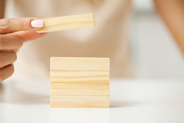 Hand, die einen Holzwürfel auf Tischhintergrund aufhebt