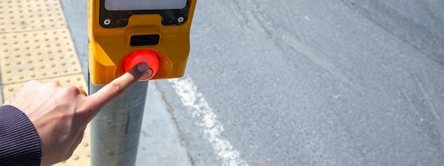 Hand, die einen Knopf an der Ampel drückt