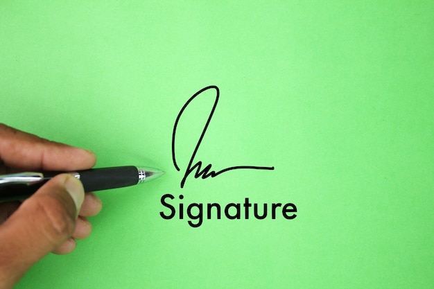 Hand, die einen Stift mit Worten und Unterschriftssymbolen hält Konzept von Vereinbarung oder Vertrag