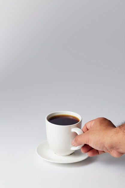 Hand, die einen weißen Tasse Kaffee hält