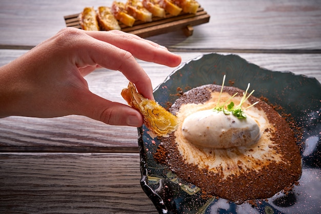 Hand, die Gebäck auf Eisdessert hält