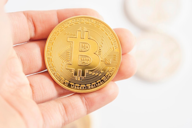 Hand, die goldene Bitcoins oder Kryptowährungssymbol auf weißem Hintergrund hält