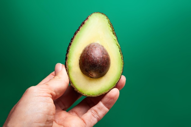 Hand, die halbe Avocado mit Grube hält