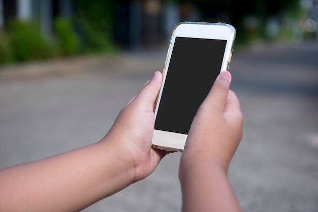 Hand, die Handy mit unscharfem Hintergrund hält