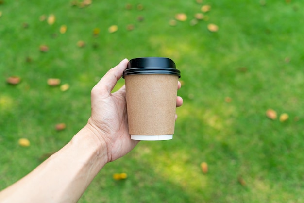 Hand, die heißen Kaffee im Glas zum Mitnehmen hält