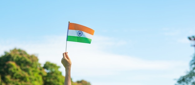 Hand, die Indien-Flagge auf Hintergrund des blauen Himmels hält. Feiertag des indischen Republiktages, glücklicher Unabhängigkeitstag und Gandhi Jayanti Konzepte