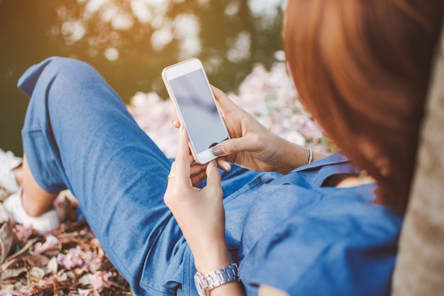 Hand, die intelligentes Telefon mit Naturhintergrund hält