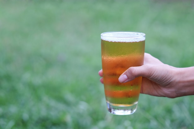 Hand, die kaltes Bier für das Trinken in der entspannenden Zeit hält