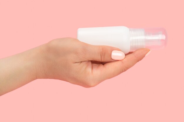 Hand, die kosmetischen Cremebehälter lokalisiert auf rosa Hintergrund hält. Verpackung von Lotion oder Creme. Beauty kosmetisches Hautpflegekonzept. Verpackung von Lotion oder Creme. Beauty kosmetisches Hautpflegekonzept.